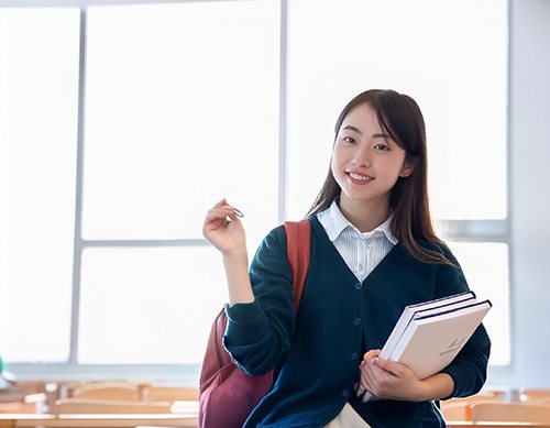本を抱えて笑顔を見せる女子生徒
